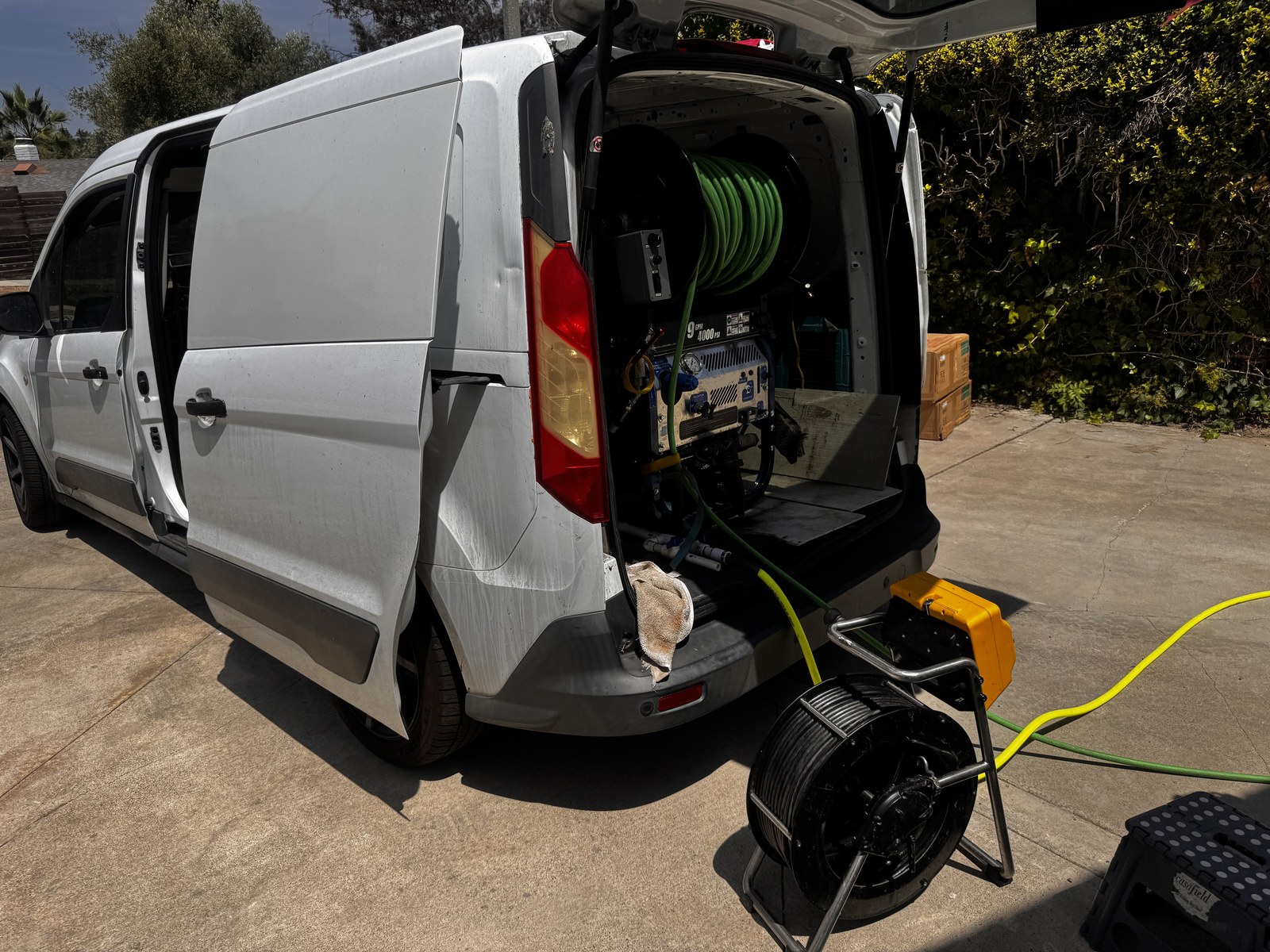 Service van with hydro jetting equipment and camera reel set up on a residential driveway