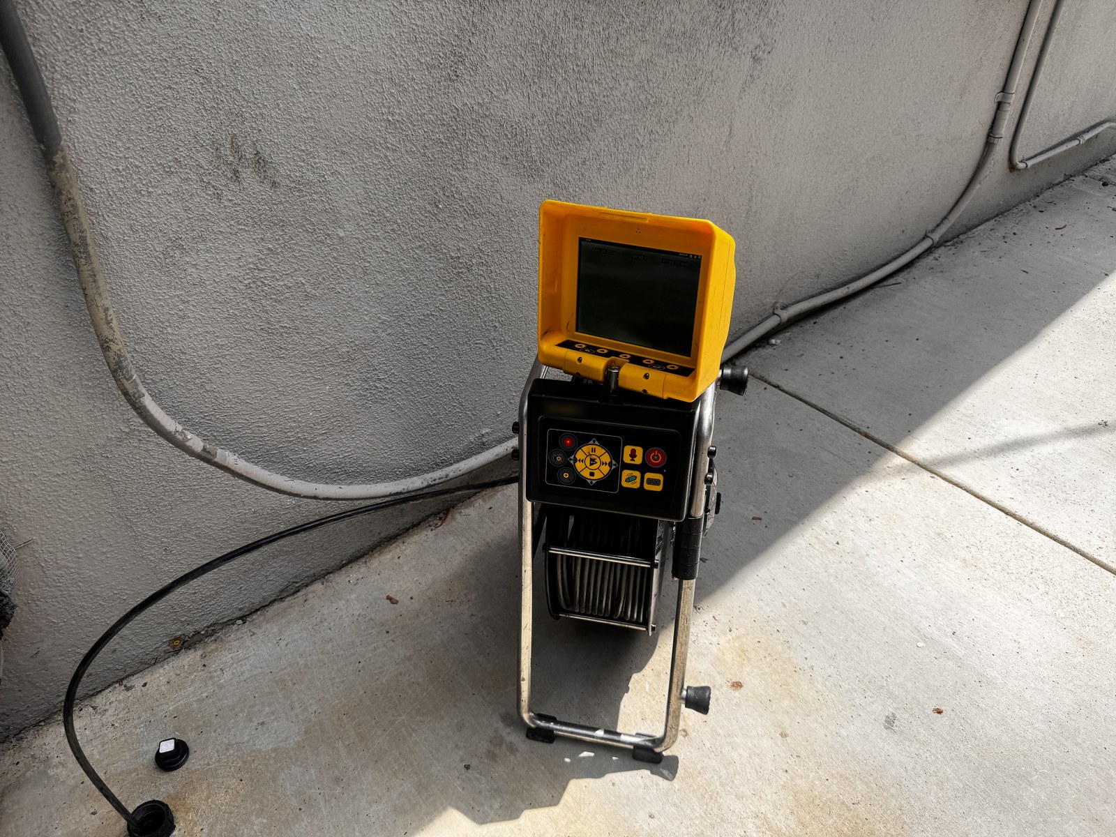Sewer inspection camera reel and monitor staged at a cleanout access point