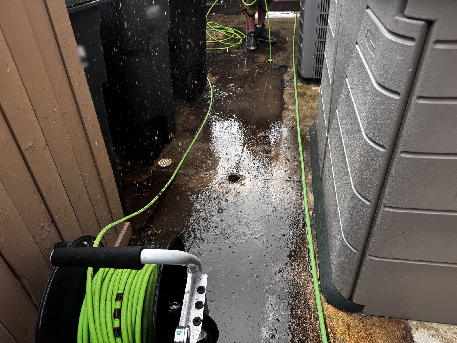 Side yard area drain with jetting equipment staged during a residential drain cleaning